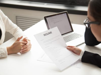 Company CEO and HR manager reading applicant resume or cv while employee waiting for questions, discussion and result during recruitment process in office. Concept of hiring, employment. Close up view