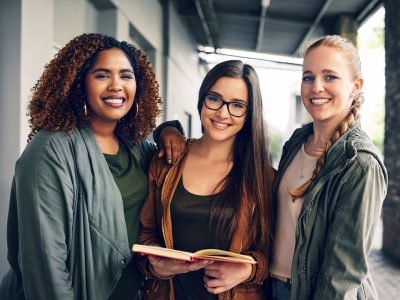 Portrait of a group of young students reading a notebook together on campus.