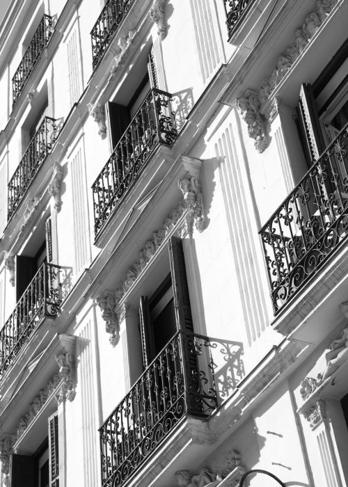 Wall of old building with small balconies in Madrid, Spain. Black and white image
