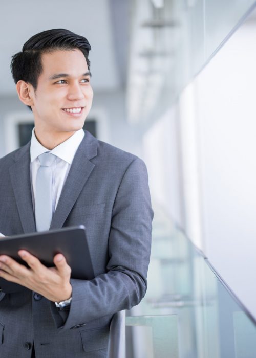 young-asian-business-man-holding-tablet-looking-away